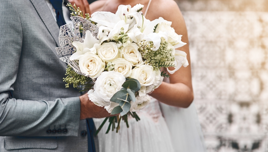A bride and groom holding a white bouquet of flowers on their wedding day