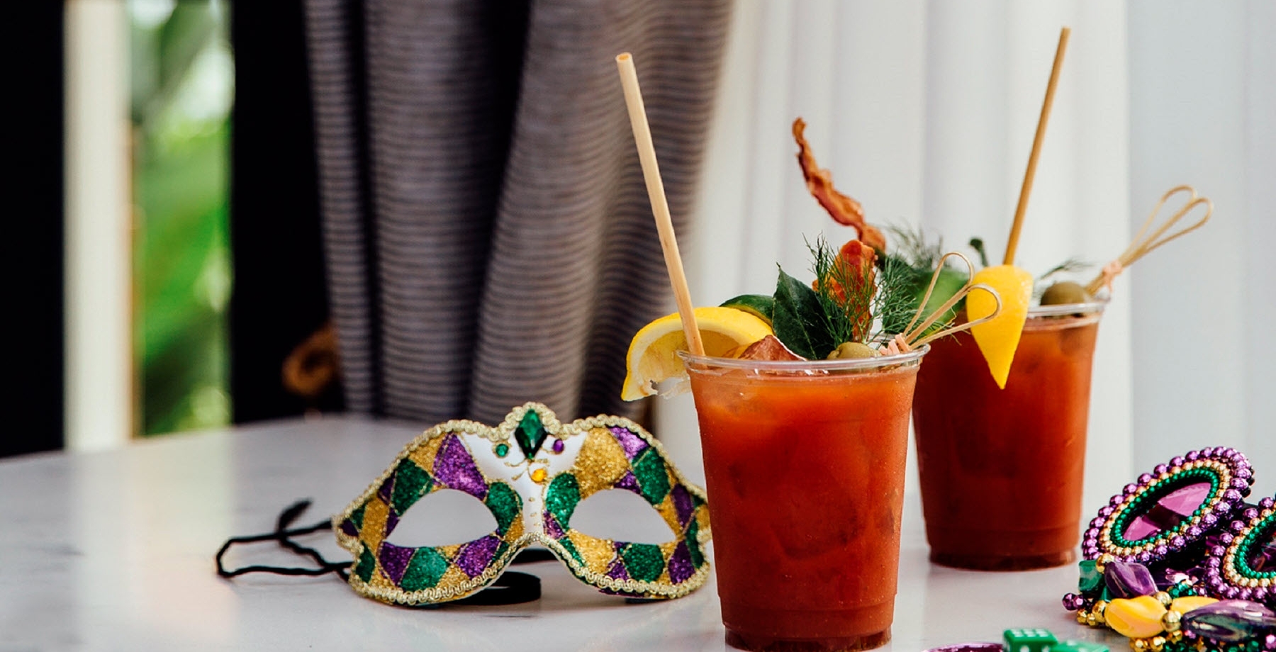 two cocktails and a mardi gras mask on a table
