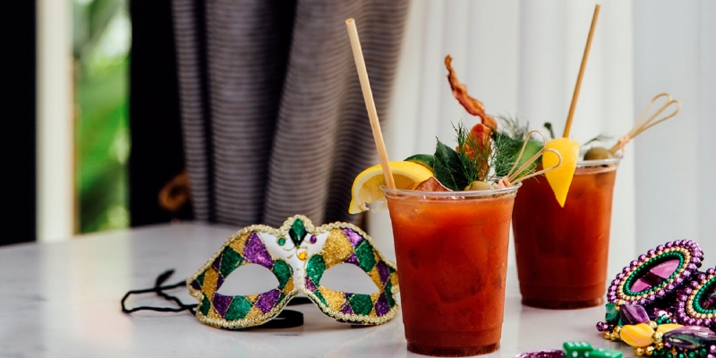 two cocktails and a mardi gras mask on a table