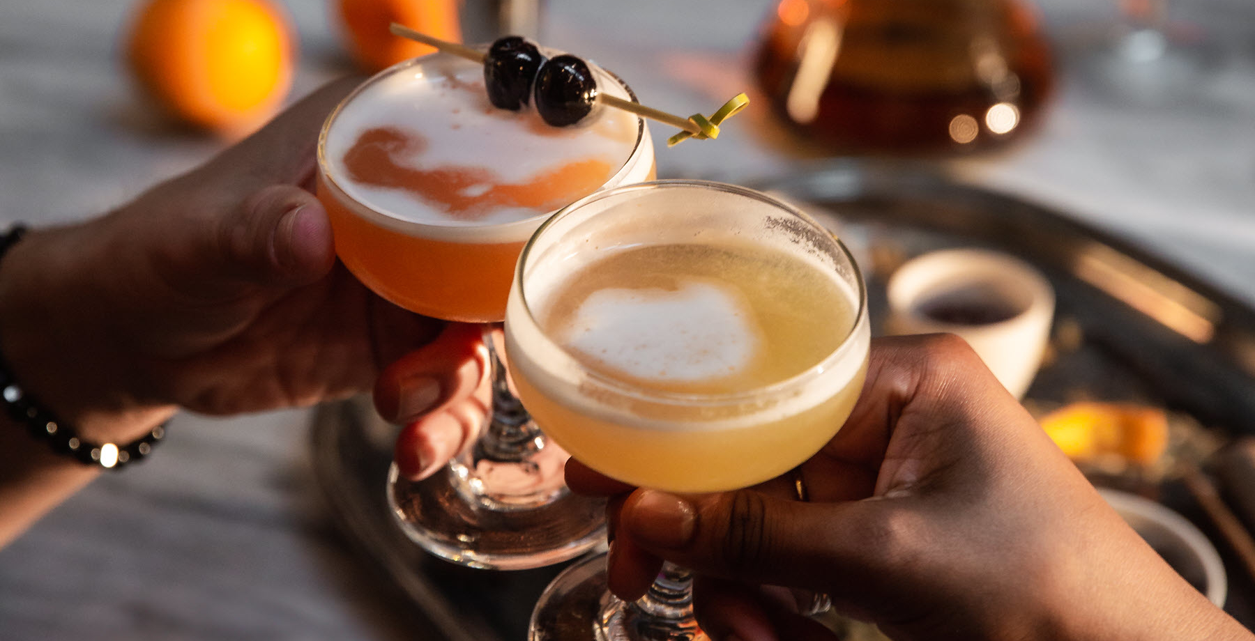 two cocktails beeing cheersed over a table