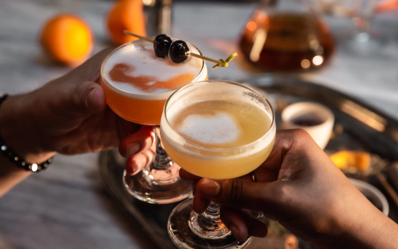 two cocktails beeing cheersed over a table