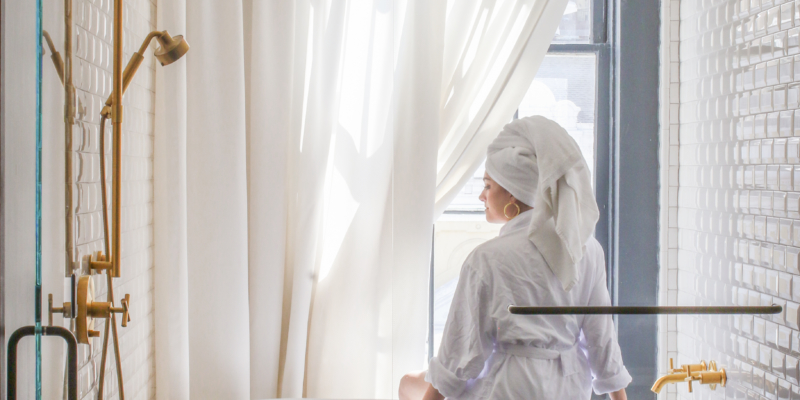 Woman in robe sitting on edge of bathtub