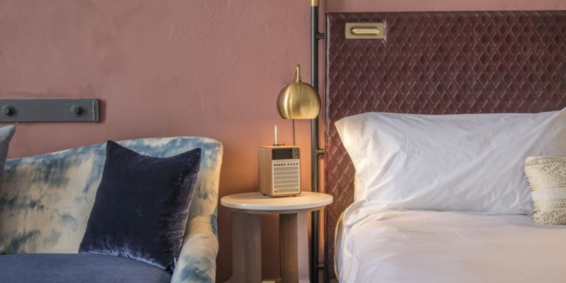 Edge of bed, side table and edge of blue couch