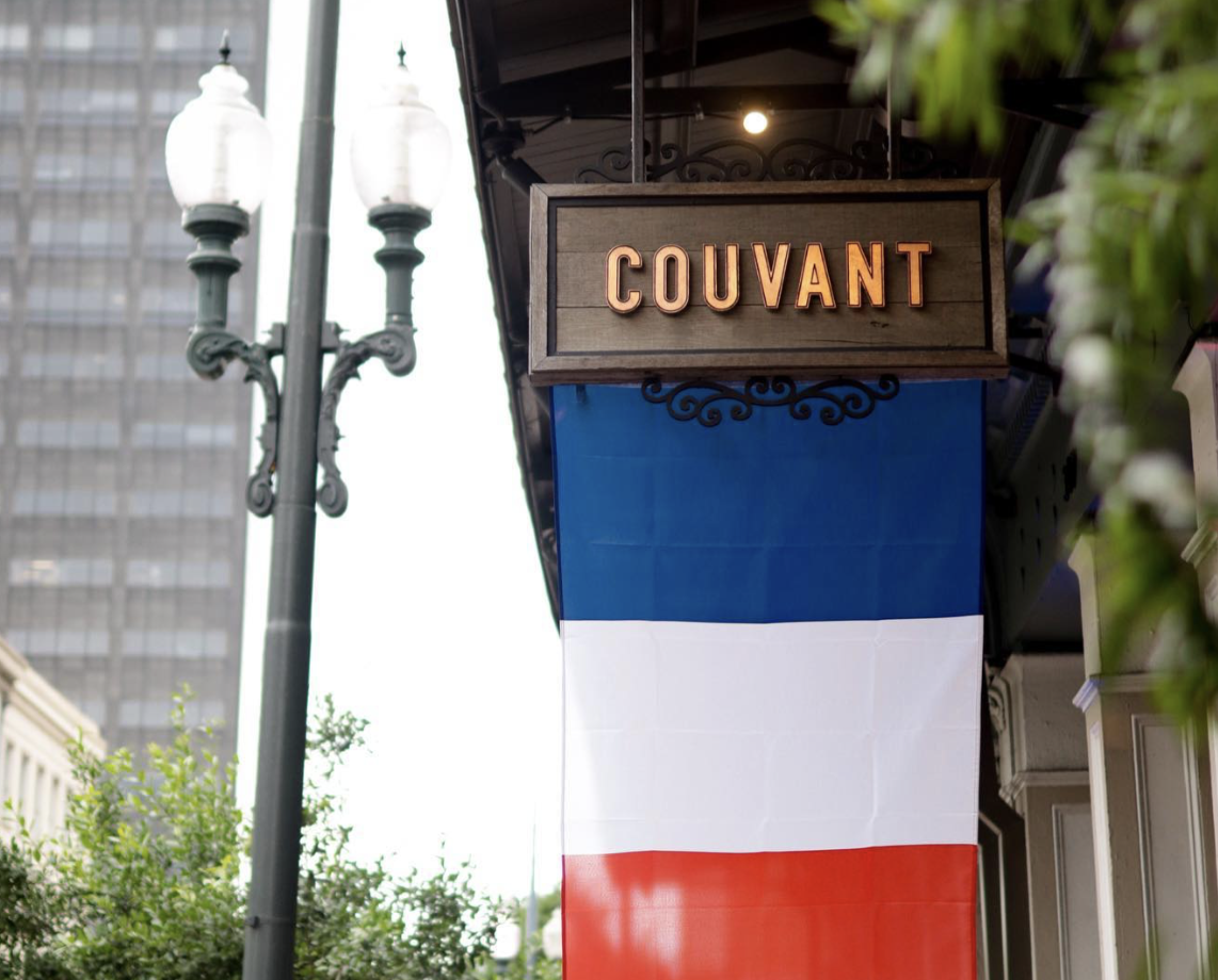 French flag hanging from sign that says Couvant