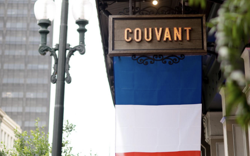 French flag hanging from sign that says Couvant