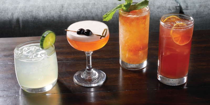 four cocktails on a wooden table