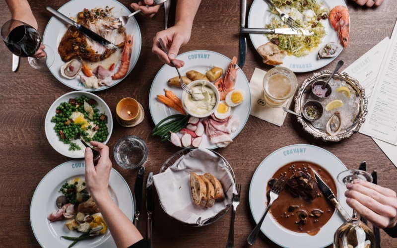 Birds Eye view of plates of food with people using forks