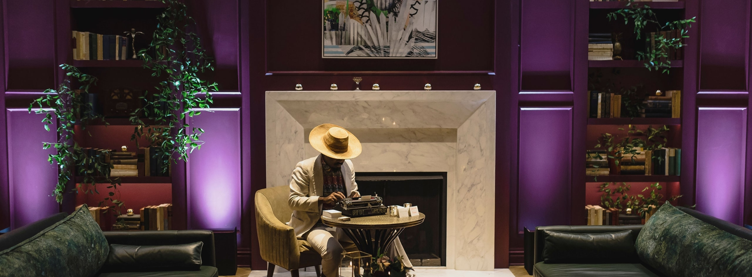 A man sitting at a typewriter in the purple lounge at The Eliza Jane Hotel in New Orleans
